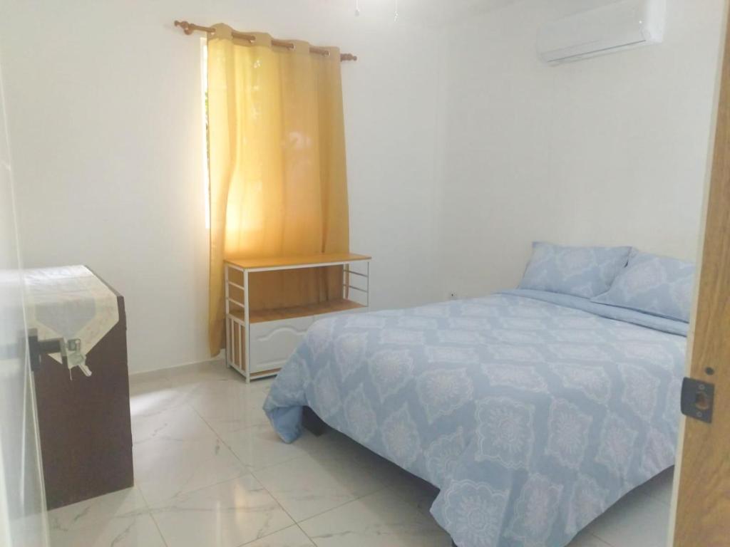 Un dormitorio con una cama y una mesita de noche. en Acogedor apartamento a cerca de la playa, en San Felipe de Puerto Plata