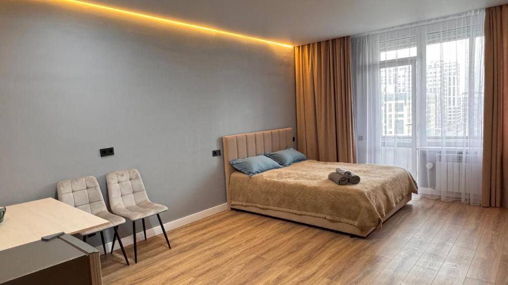 a bedroom with a bed and a table and chairs at Апартаменты Барыс Арена in Astana