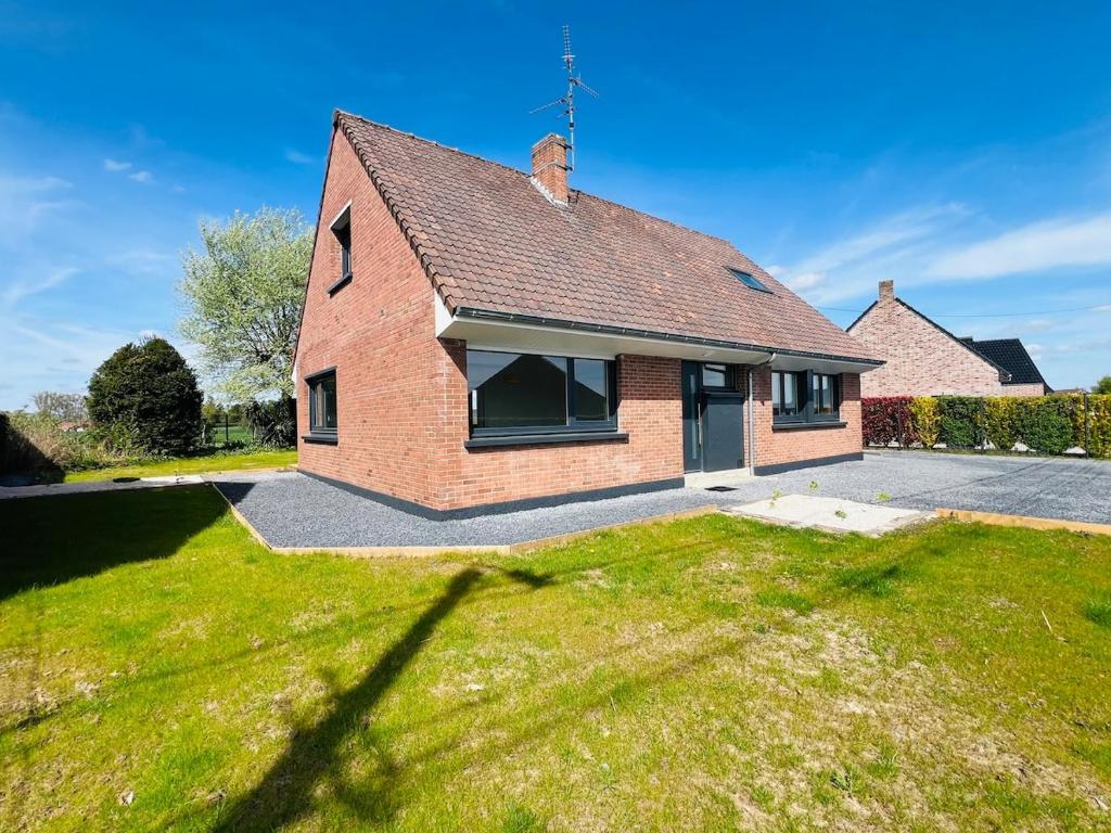 une maison en brique avec une pelouse dans l'établissement La Joliette, maison 5 chambres, à Rumegies
