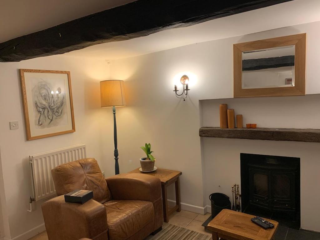 a living room with a chair and a fireplace at Cute cob cottage in Winterborne Stickland