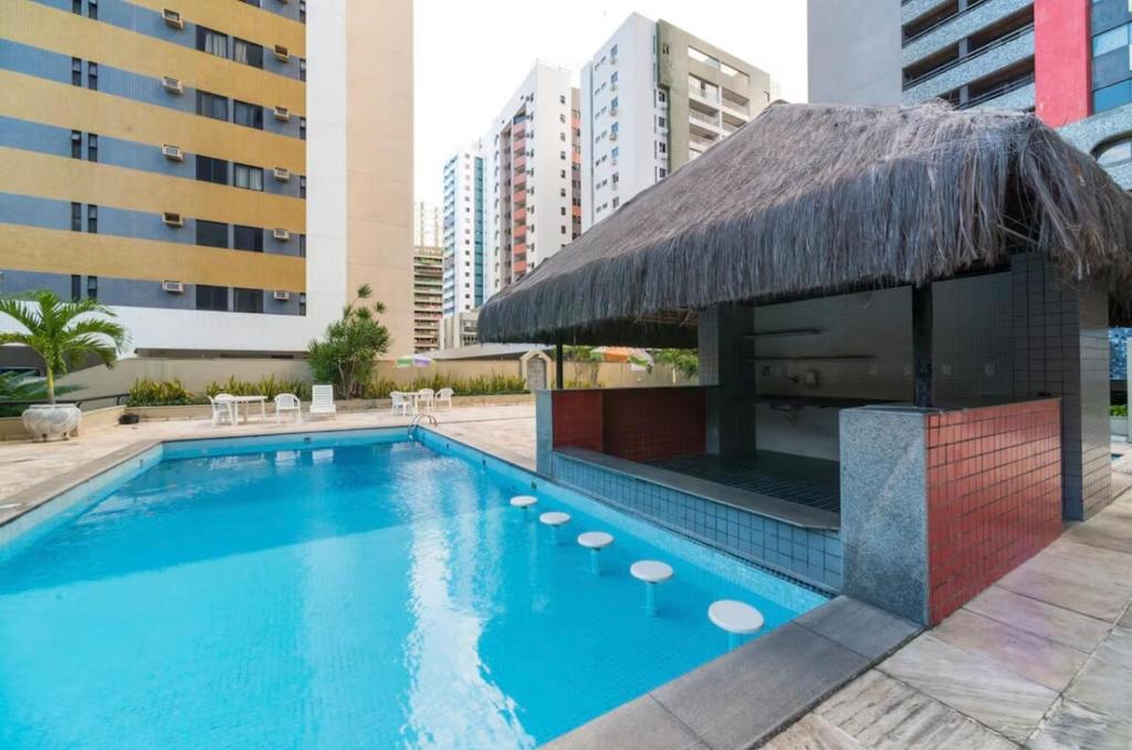 a swimming pool with a straw umbrella and a building at Apartmento em Boa Viagem in Recife
