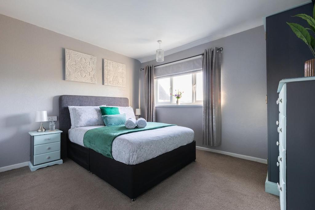 a bedroom with a bed with green and white sheets and a window at Clicketts - 3-Bedroom, Full Entire House, Sleeps 6 guests, Free wifi, Street Parking, Smart TV, Basildon, Essex London in Basildon