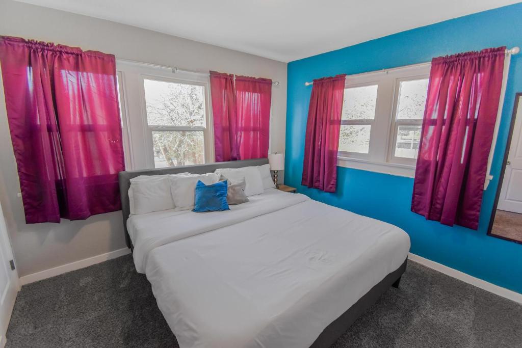 Un dormitorio con una gran cama blanca con cortinas rosas. en Cozy upper unit great for family visiting Zoo medica campus and downtown, en Denver