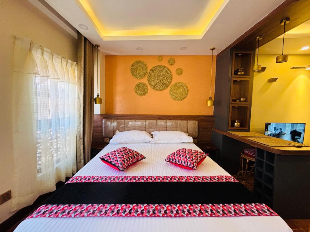 a bedroom with a bed with two red pillows at The Ganesh Kuti in Pātan