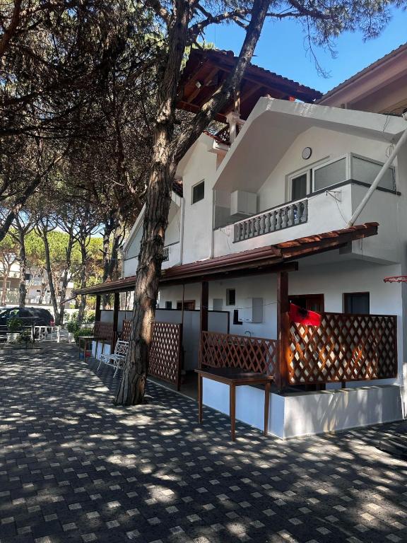 a white house with a tree and a bench at Vila Reni Apartament in Golem