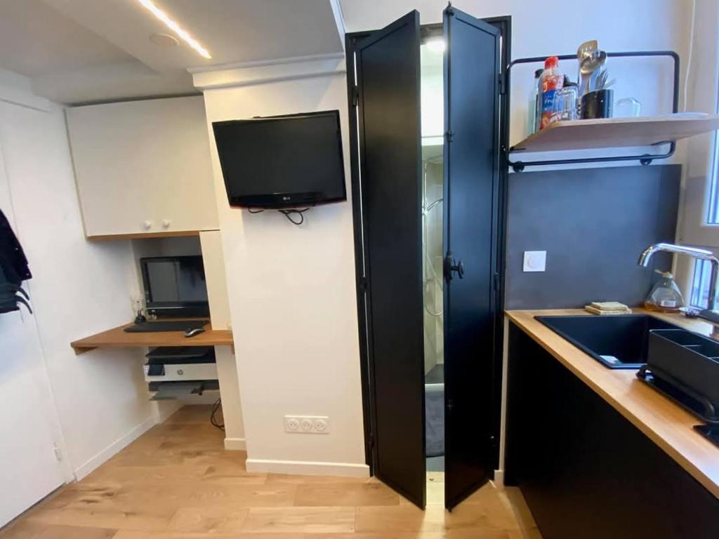 - une cuisine avec évier et une télévision dans la chambre dans l'établissement Studio au cœur de paris, à Paris
