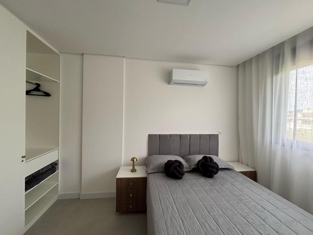 a bedroom with a large bed and a window at Apto em Home Clube na Praia de Palmas in Governador Celso Ramos