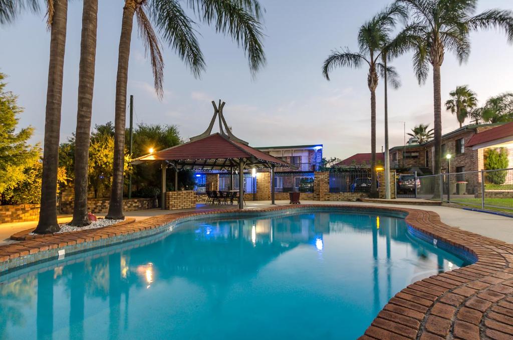 a swimming pool with palm trees and a gazebo at Centrepoint Midcity Motor Inn in Warwick