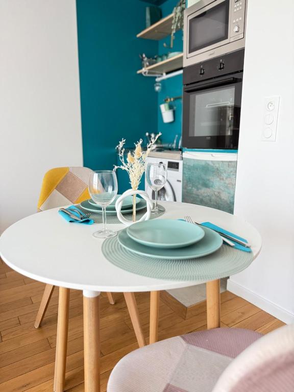 - une table blanche avec des assiettes et des verres dans la cuisine dans l'établissement La chatillonnaise, à Châtillon