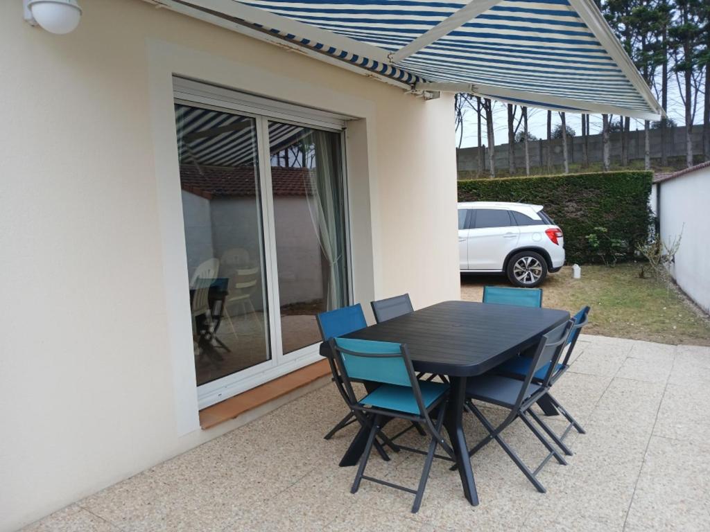 a black table and blue chairs on a patio at Notre-Dame-de-Monts (85) - Maison de vacances 61m² environ - 8 personnes - FR-1-540-164 in Notre-Dame-de-Monts