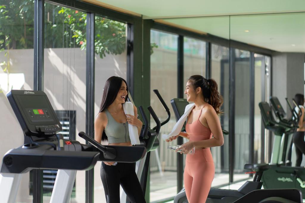 A bright gym with treadmills and large windows overlooking greenery.