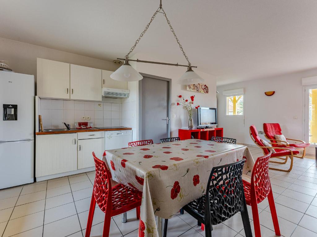 une cuisine avec une table et des chaises rouges et une cuisine avec des placards blancs dans l'établissement Appartement Confortable Proche Océan avec Parking et Terrasse - 7 Pers - FR-1-521-244, à Biscarrosse