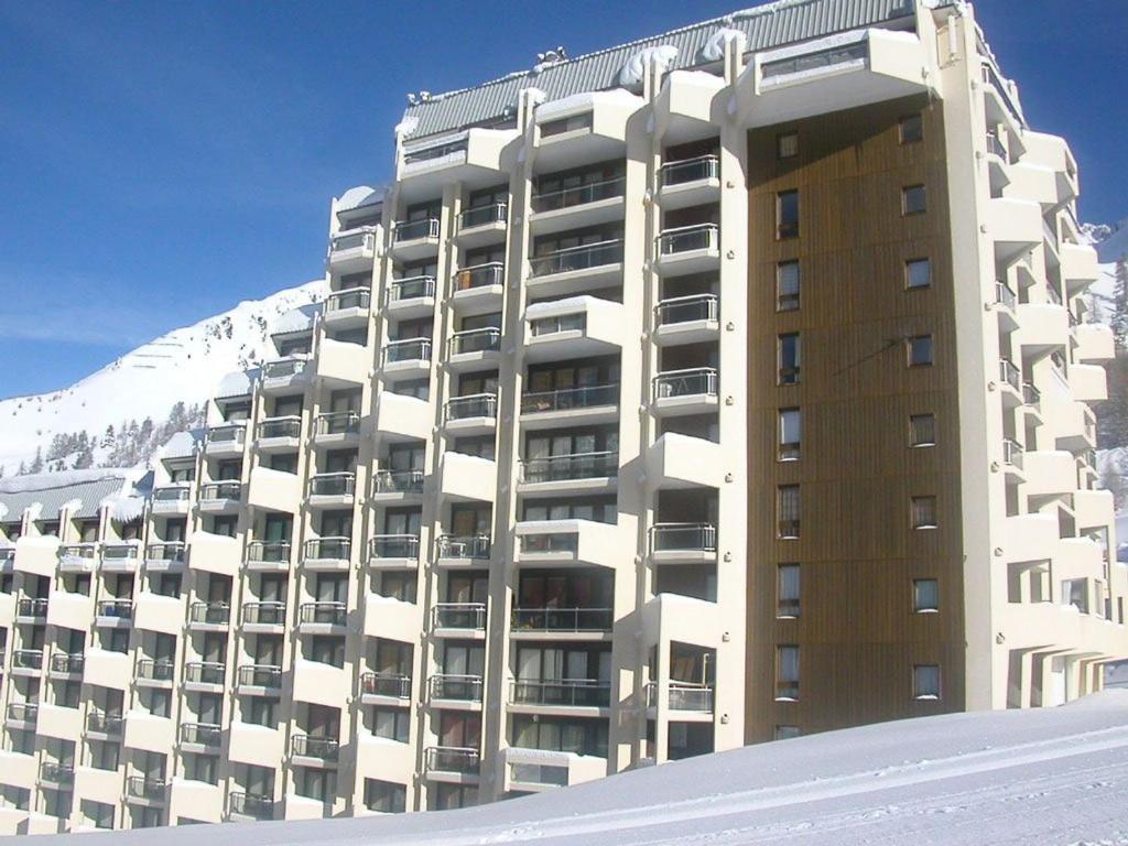 un grand bâtiment avec une montagne enneigée derrière dans l'établissement Studio rénové au pied des pistes avec internet collectif - FR-1-292-229, à Isola