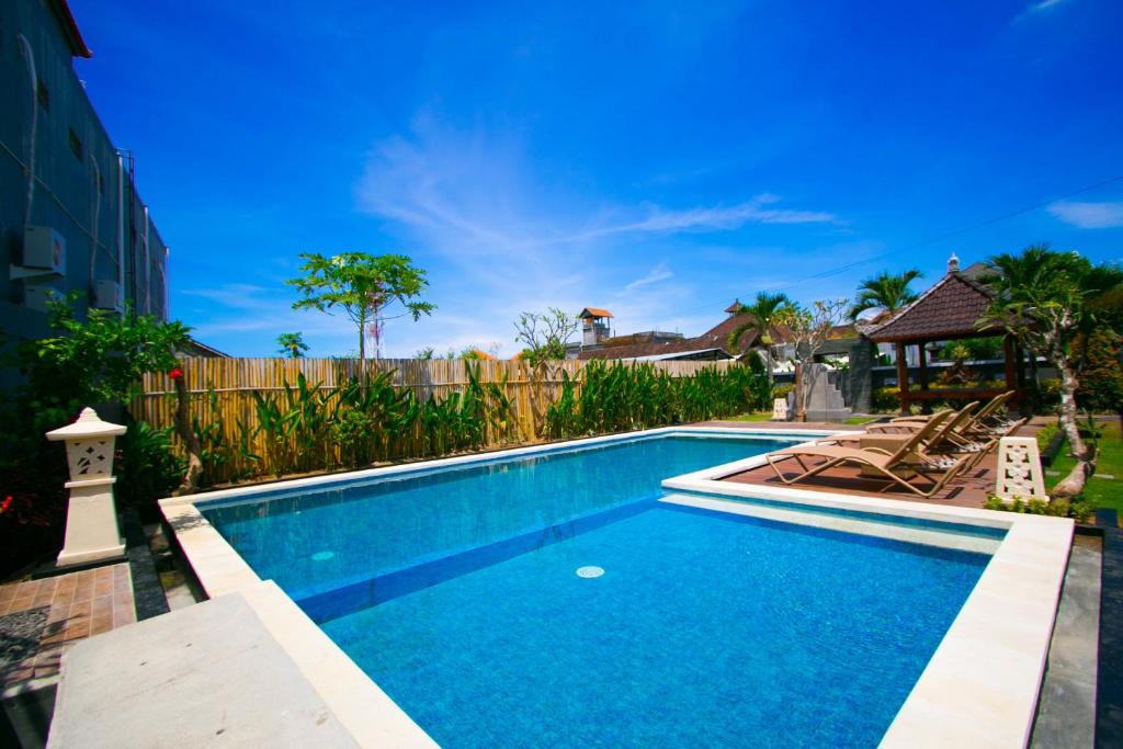 a swimming pool with two lounge chairs next to it at Srikandi Inn in Jimbaran