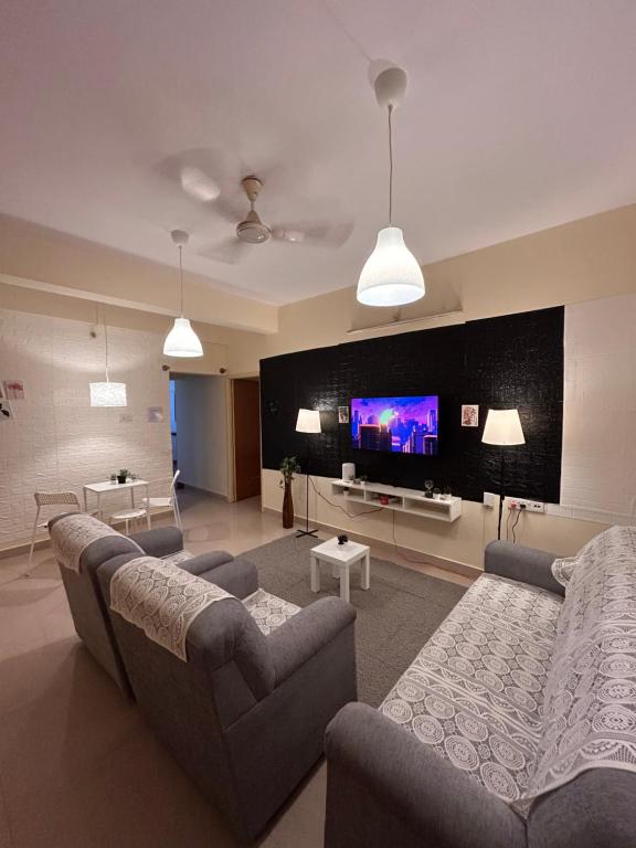 a living room with two couches and a flat screen tv at Electrifying 2 BHK Getaway in Bengaluru
