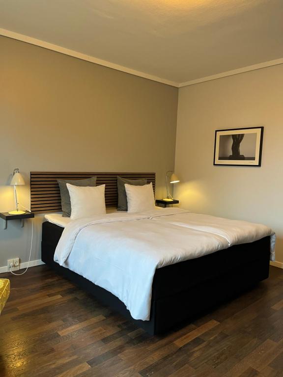 a bedroom with a large bed with white sheets at First Hotel Grand in Odense