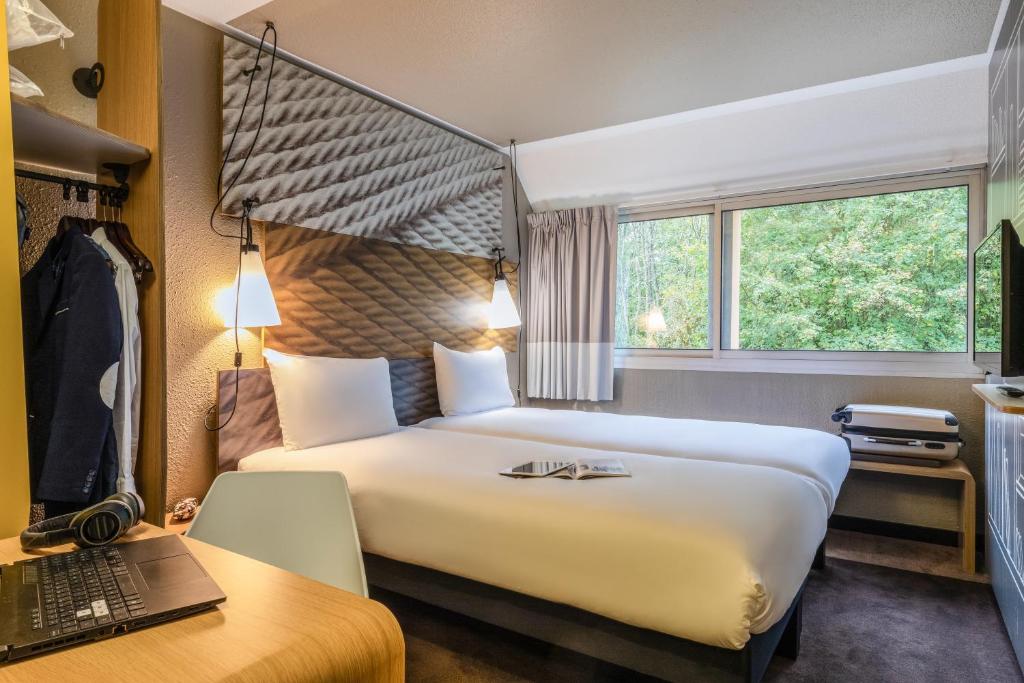 Cette chambre comprend un lit, un bureau et un ordinateur portable. dans l'établissement ibis Velizy Jouy-En-Josas, à Jouy-en-Josas