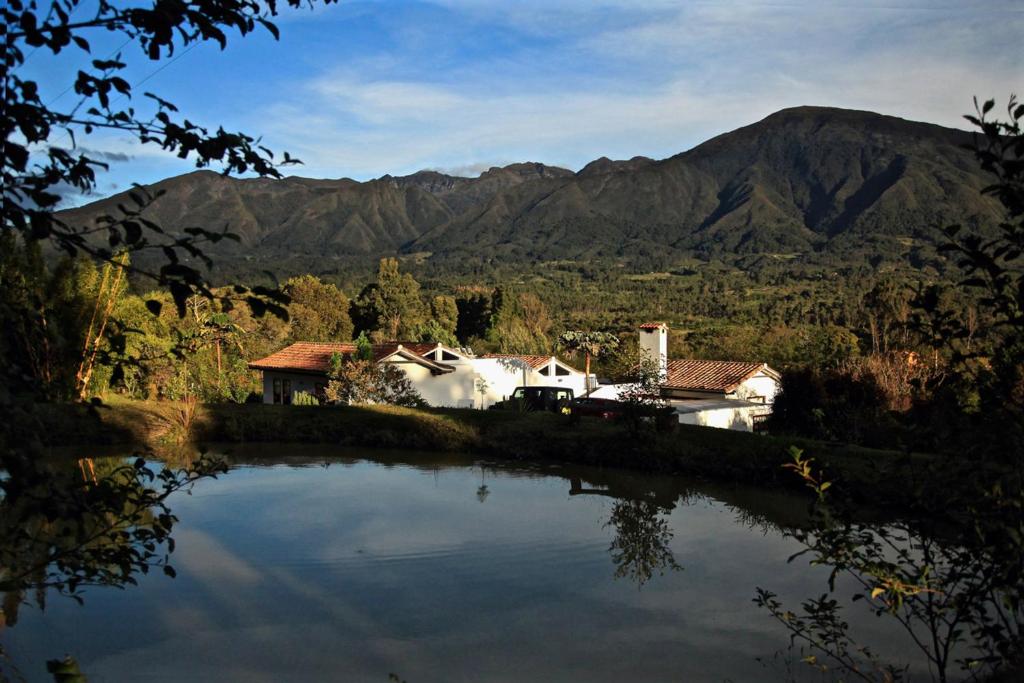 una casa y un lago con montañas en el fondo en PASSADHI Ayurveda & Yoga Retreat, en Villa de Leyva