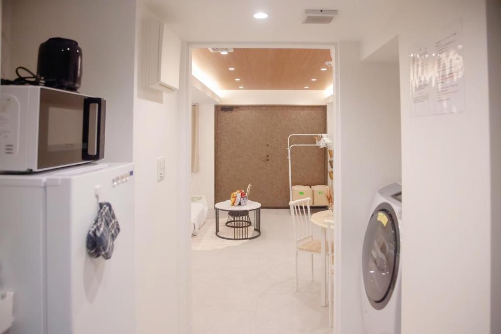 ein weißer Raum mit einer Mikrowelle und einem Tisch in der Unterkunft 森下小屋 in Tokio
