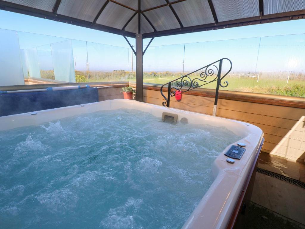 a jacuzzi tub with an umbrella on a deck at Tataramoa in Penryn
