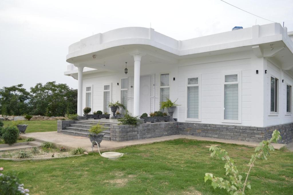 a white house with a lawn in front of it at Astoria Hill Resort in Mingora