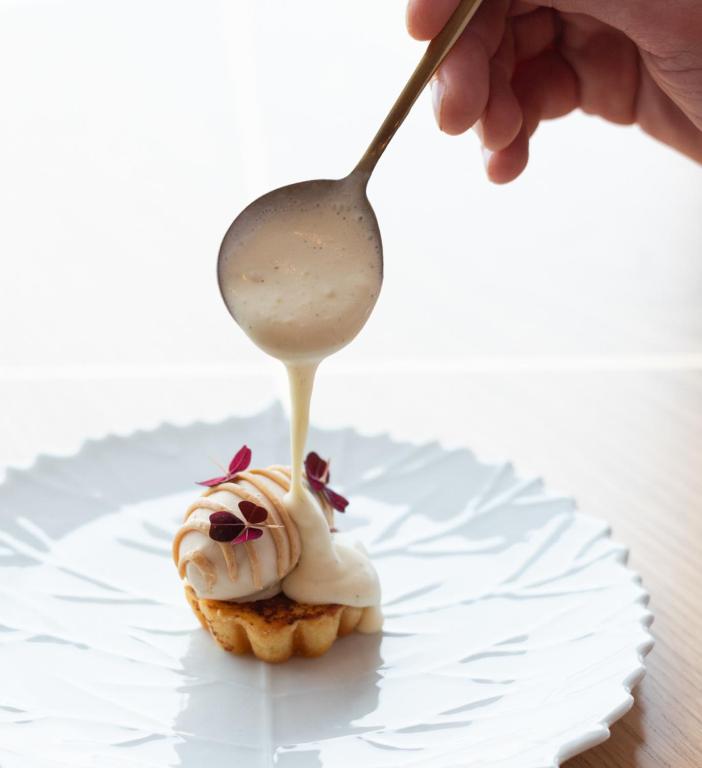 a hand holding a spoon over a cupcake with icing at Boutique Hotel Glacier in Grindelwald