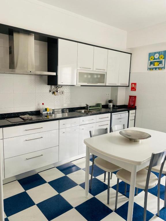 a kitchen with white cabinets and a table with chairs at SwordFish City Center Apartment in Peniche