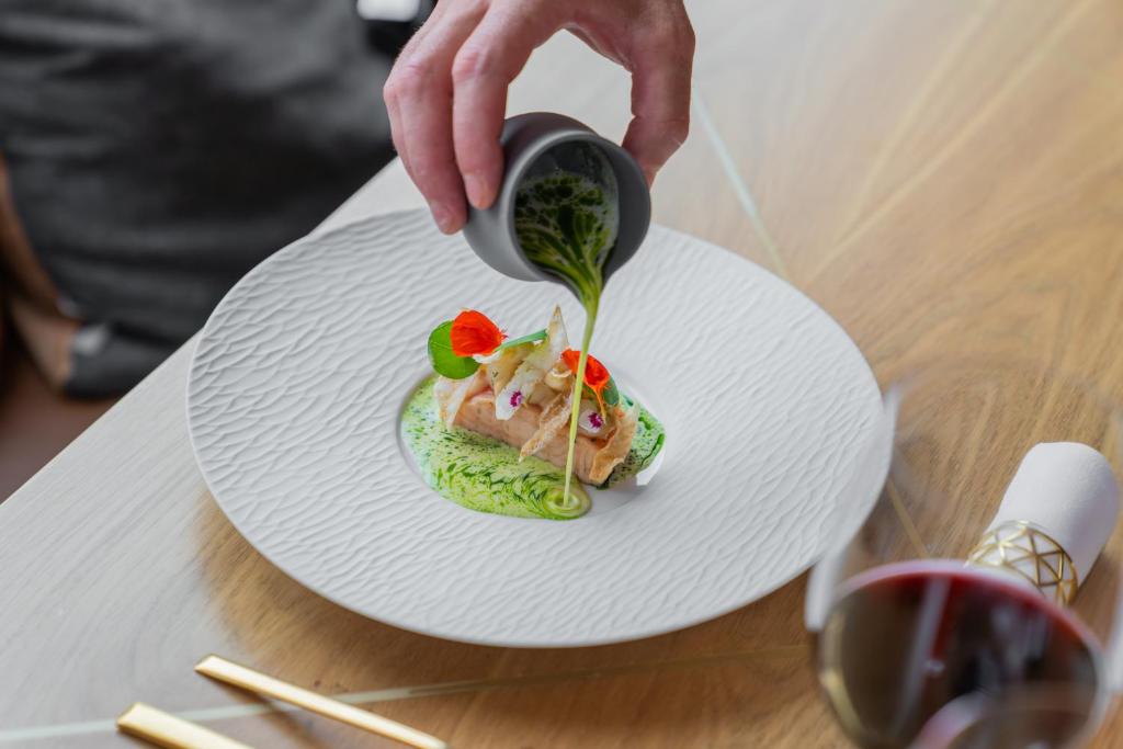 a person pouring sauce onto a plate of food at Boutique Hotel Glacier in Grindelwald
