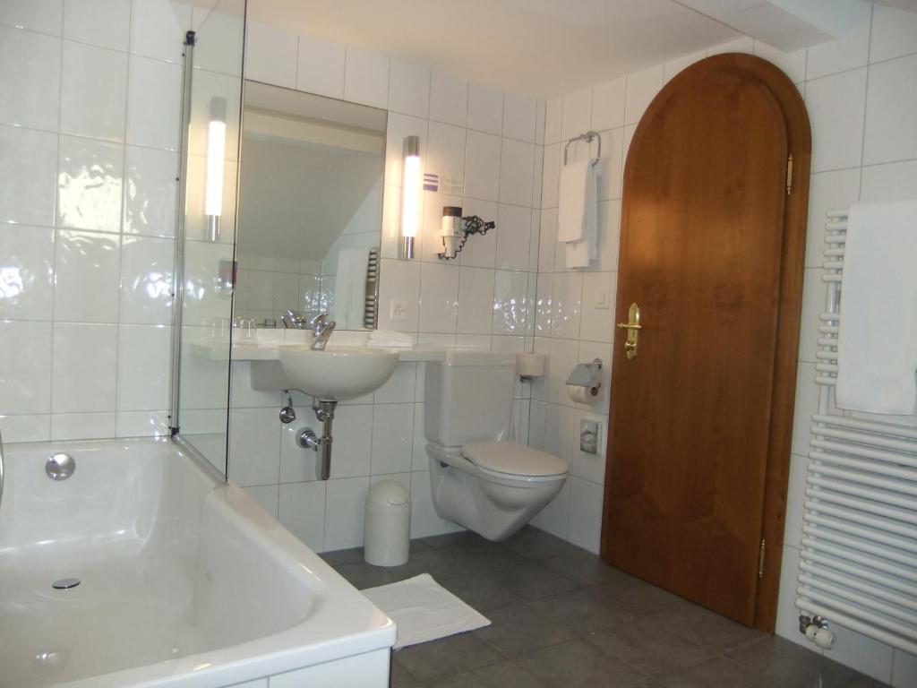 a bathroom with a toilet and a sink and a tub and a mirror at Hotel Hecht Appenzell in Appenzell