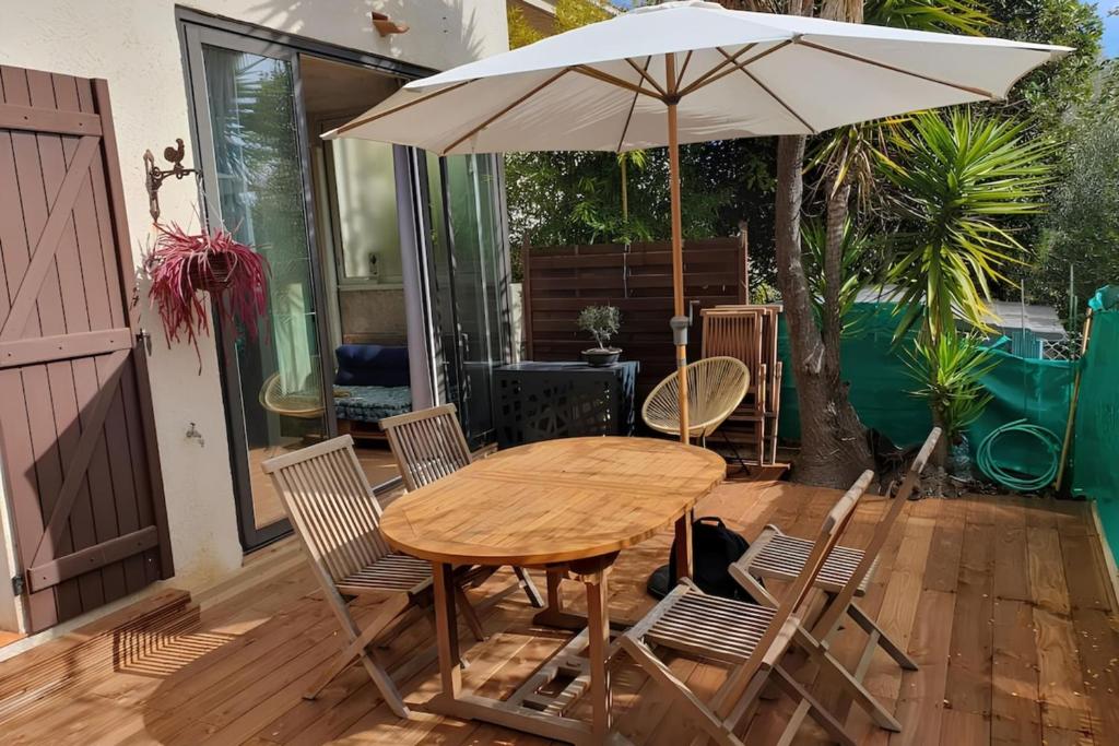 - une table et des chaises en bois avec un parasol sur la terrasse dans l'établissement Le Romarin - Air conditioning and 1 private parking space, à Six-Fours-les-Plages