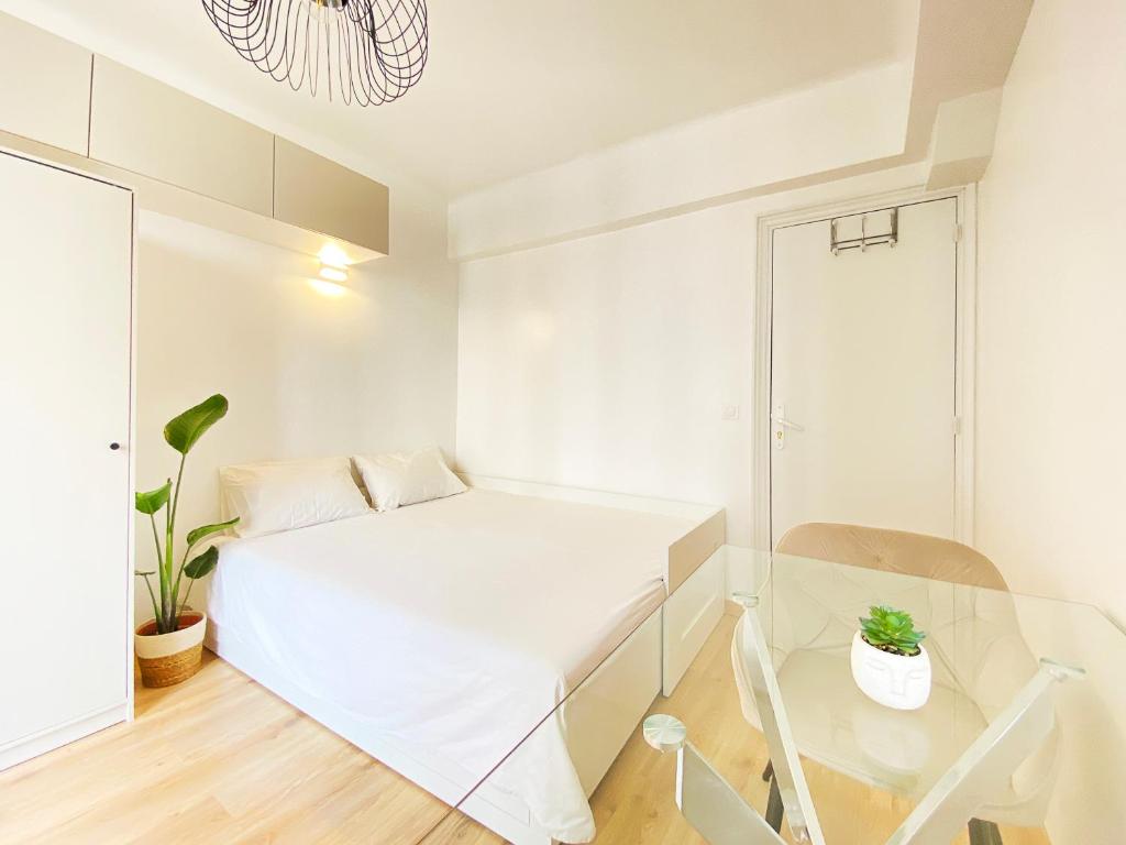 une chambre blanche avec un lit et une table en verre dans l'établissement Cosy and lovely flat close to Montparnasse, à Paris
