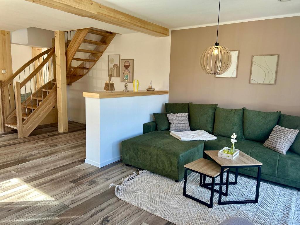 a living room with a green couch and a table at Urlaub am Schwarzbach mit Sauna und Whirlpool Haus Johanna in Butgenbach