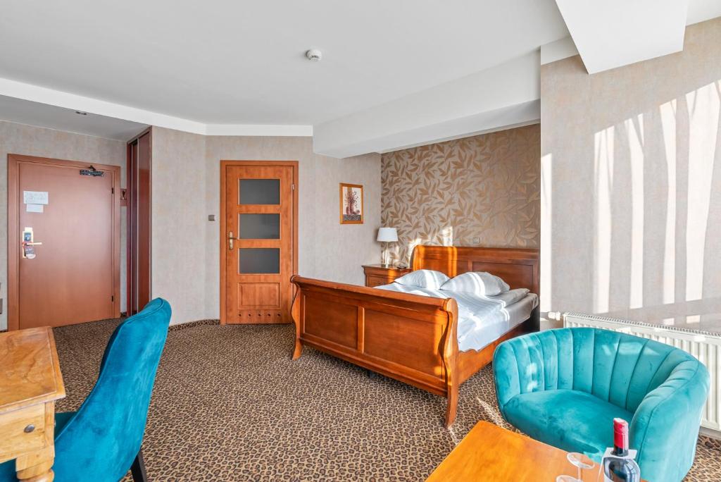 a bedroom with a bed and a blue chair at Hotel Diament Vacanza Katowice - Siemianowice in Siemianowice Śląskie