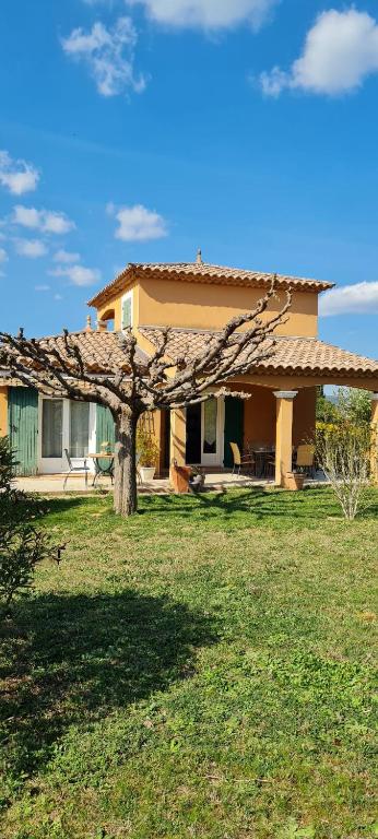 une maison avec un arbre en face d'une cour dans l'établissement Maison Gorges du Gardon, à Collias