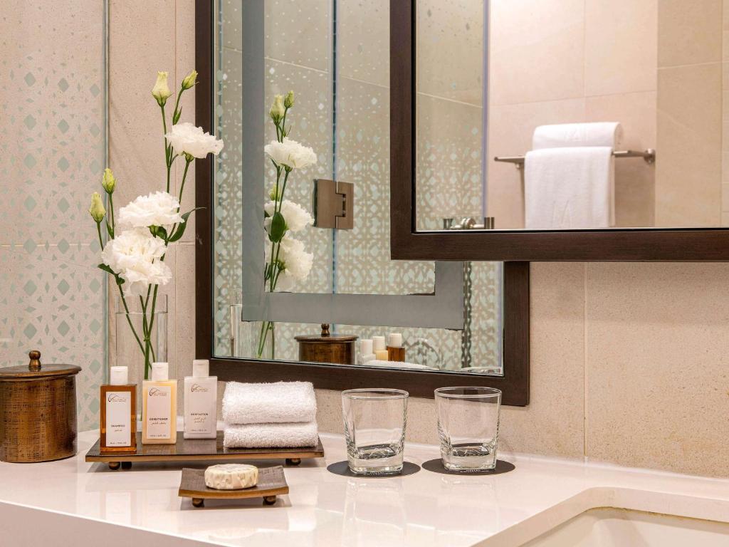 a bathroom with a sink and a mirror at Alwadi Hotel Doha - MGallery Collection in Doha