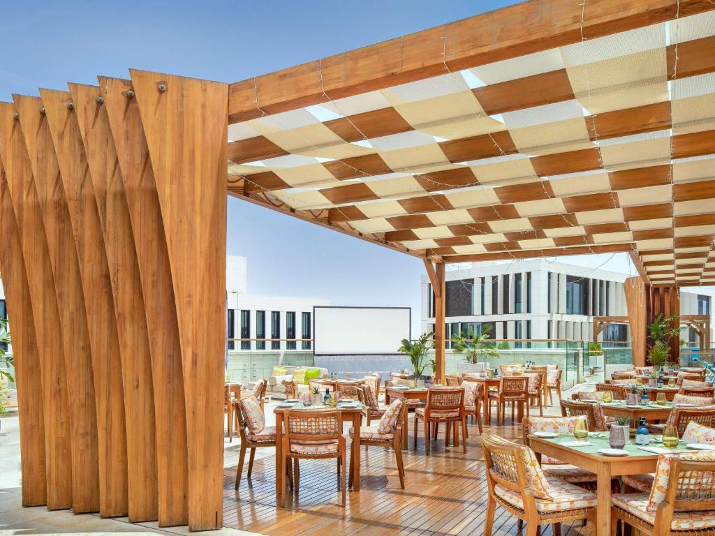 an outdoor dining area with tables and chairs at Alwadi Hotel Doha - MGallery Collection in Doha