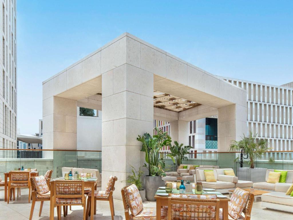a patio with tables and chairs in front of a building at Alwadi Hotel Doha - MGallery Collection in Doha