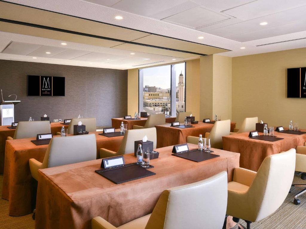 a restaurant with tables and chairs and a large window at Alwadi Hotel Doha - MGallery Collection in Doha