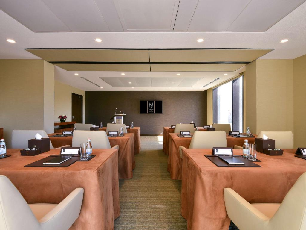 a conference room with tables and chairs and a podium at Alwadi Hotel Doha - MGallery Collection in Doha