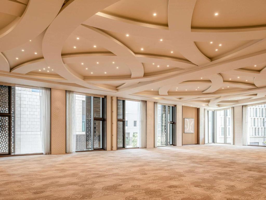 a large room with a coffered ceiling and windows at Alwadi Hotel Doha - MGallery Collection in Doha