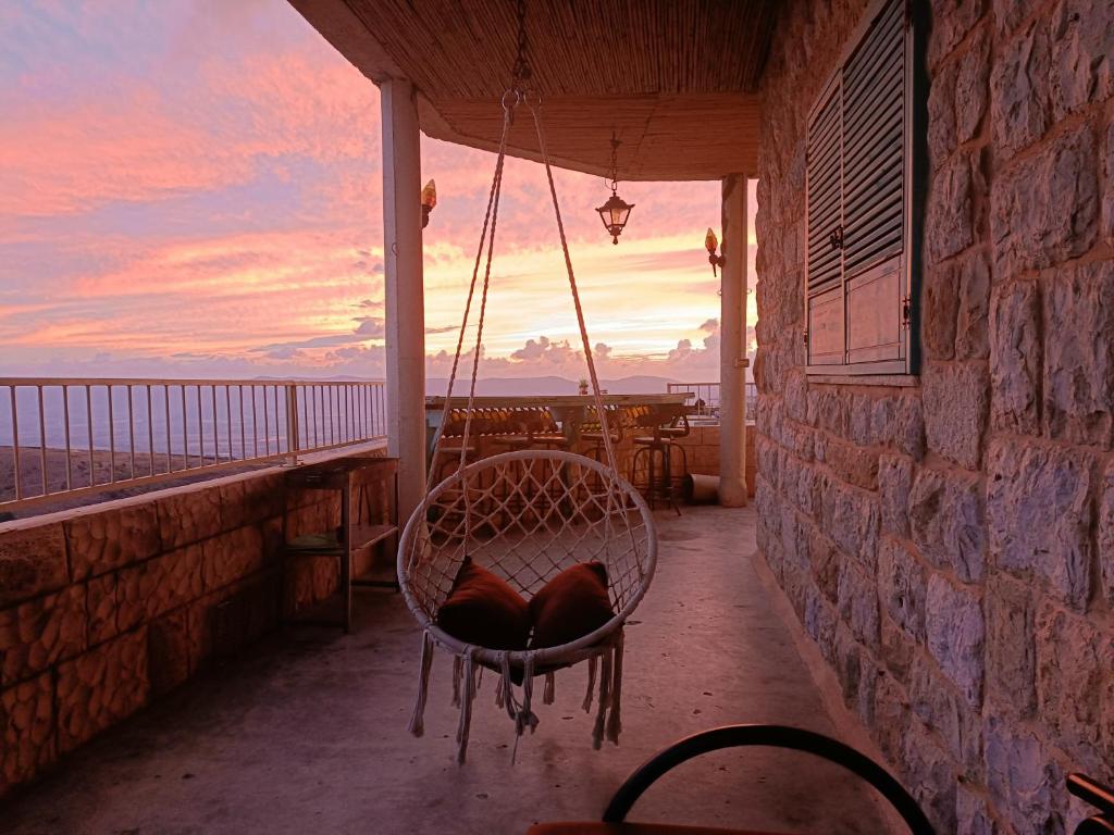 une chaise sur un balcon avec vue sur l'océan dans l'établissement צימר old school, à Ein Kinya