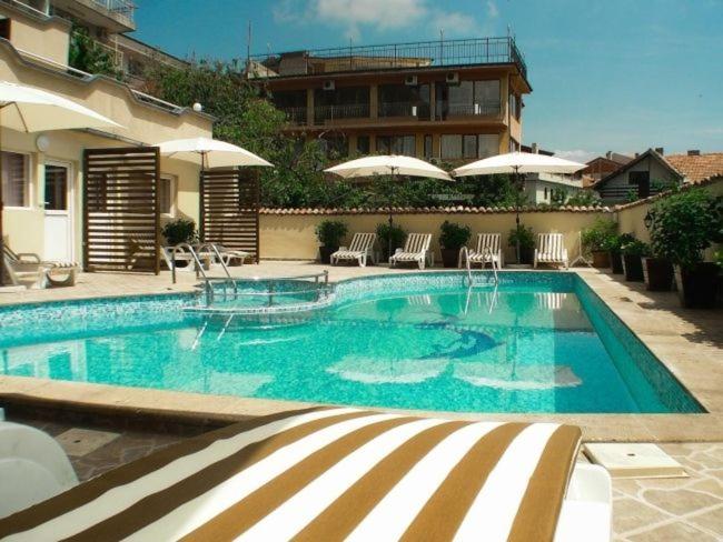 a swimming pool with chairs and umbrellas next to a building at Къща за гости Черно море in Sveti Vlas