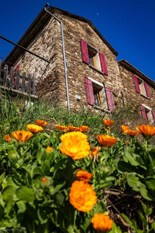 un bâtiment avec des fenêtres rouges et des fleurs orange devant lui dans l'établissement Mas Soubeyran, à Saint-Michel-de-Dèze