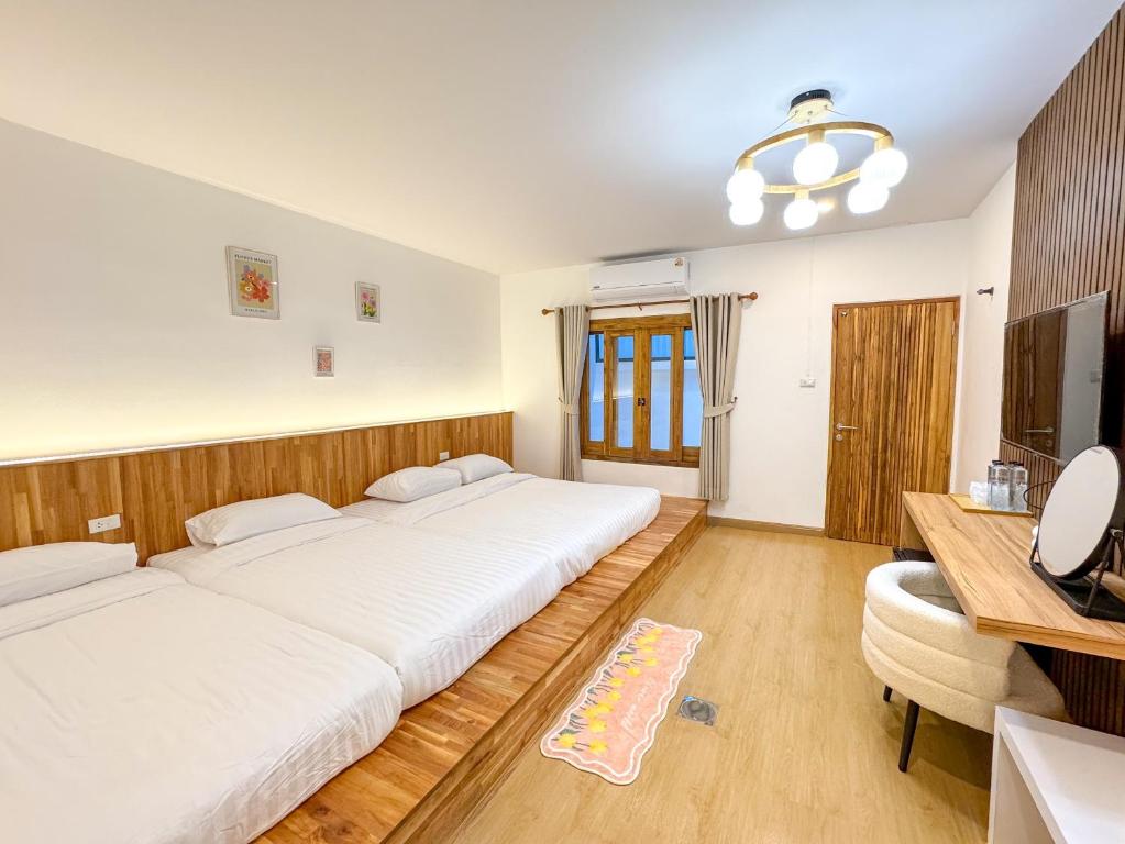 a bedroom with two beds and a desk and a television at Jinbo White House Betong in Betong