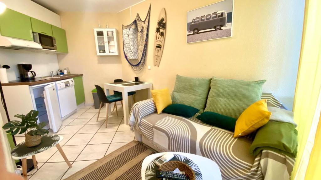 un salon avec un canapé et une cuisine dans l'établissement Appartement dans résidence les jardins de Neptune saint cyprien plage,piscine, jeux enfants, à Saint-Cyprien