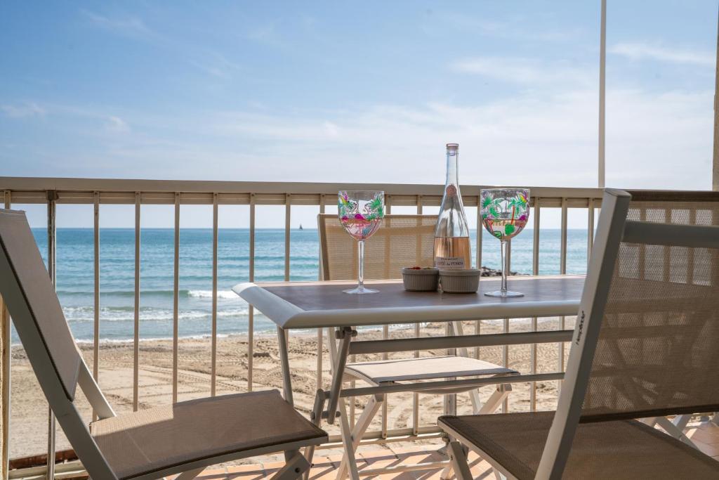 a table and chairs on a balcony with the beach at Les Pieds dans l'eau YourHostHelper in Palavas-les-Flots