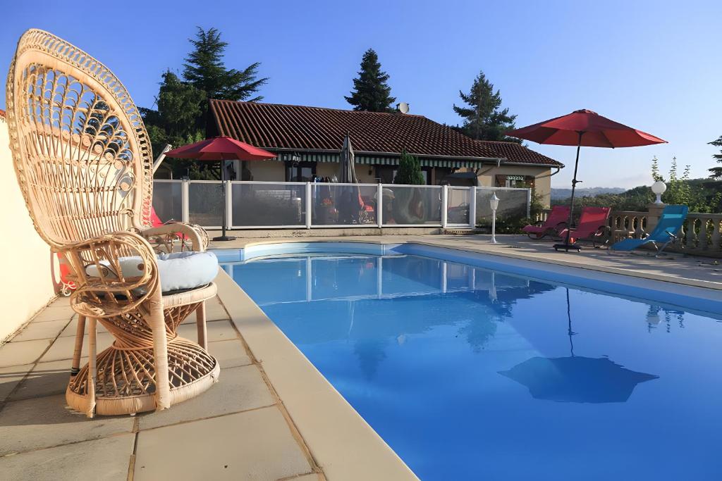 a wicker chair sitting next to a swimming pool at Chez Louis in Revel-Tourdan