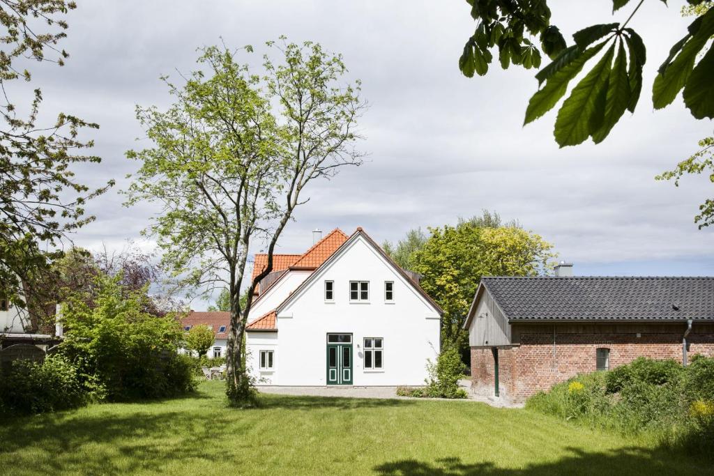 a white house with a red roof at Leuchtturnwohnung in Pommerby
