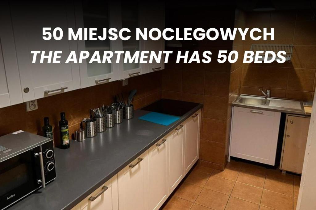 a kitchen with a counter with a sink and a microwave at 50 People Bis Apartment in Kraków