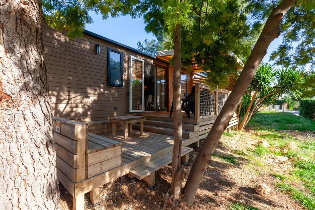 une cabine avec une terrasse en bois à côté d'un arbre dans l'établissement Camping Lou Soulei 218, à Carry-le-Rouet